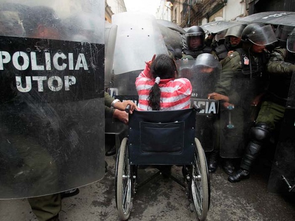Mulher numa cadeira de rodas em confronto com a polícia