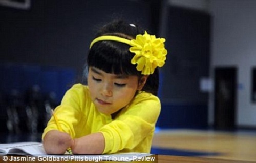 Talento: Annie, que nasceu na China, segura o lápis entre os braços.