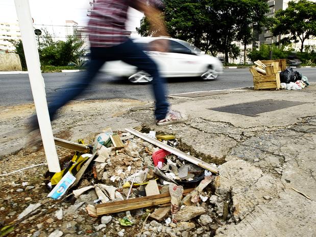 Pedestre salta por cima de um grande buraco na calçada da avenida Engenheiro Luís Carlos Berrini, em São Paulo. Foto: Bruno Santos / Terra