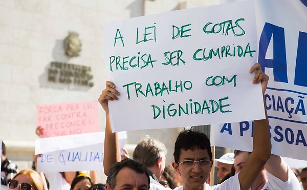 Manifestante exibe cartaz durante protesto pelos direitos de pessoas com deficiência em frente à Prefeitura de São Paulo