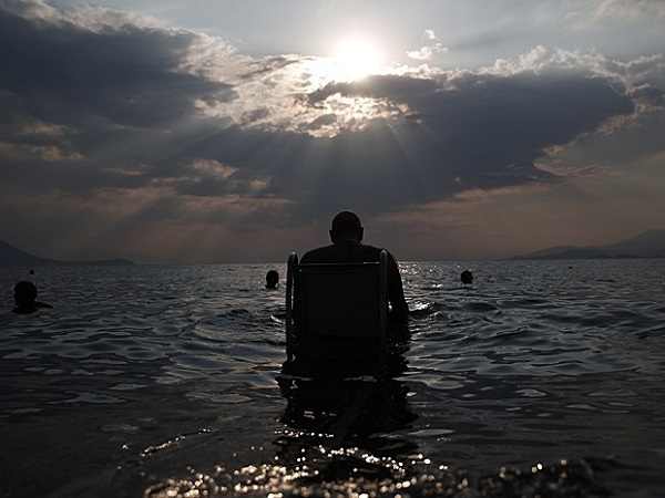 Lefteris Theofilou, de 52 anos, que sofre de paraplegia, entra no mar com a ajuda do Seatrac, dispositivo movido a energia solar que permite que pessoas com deficiência entrem e saiam do mar de forma autônoma, em praia de Alepochori, no oeste de Atenas, no dia 12 de julho (Foto: Yorgos Karahalis/Reuters)