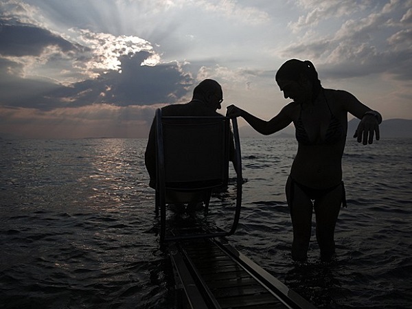 Lefteris Theofilou, que sofre de paraplegia, é ajudado pela mulher, Eleni, de 37 anos, que tem paralisia cerebral. Dispositivo a energia solar ajuda pessoas com deficiência a nadar (Foto: Yorgos Karahalis/Reuters)