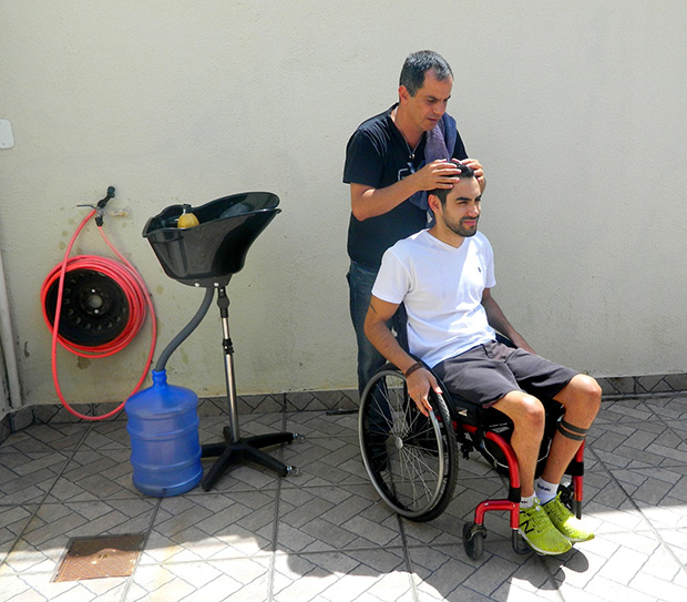 O empresário José Valente prepara os cabelos do cliente Leonardo Alencar, que é cadeirante há seis anos. Foto: Jéssica Nascimento/UOL
