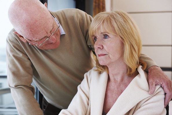 Homem com a mão nos ombros de uma paciente com Mal de Alzheimer