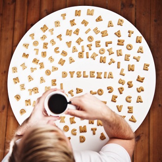 Imagem de um homem bebendo café e observando as letras e a palavra dislexia