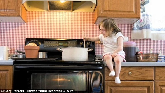 Hora do jantar: Bridgette Jordan leva tempo para se sentar na superfície da pia da cozinha enquanto prepara comida.