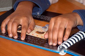 Garoto com deficiência visual lendo livro em braille