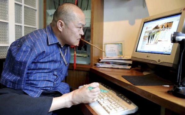 Huang Guofu em frente ao computador, digitando com o pé