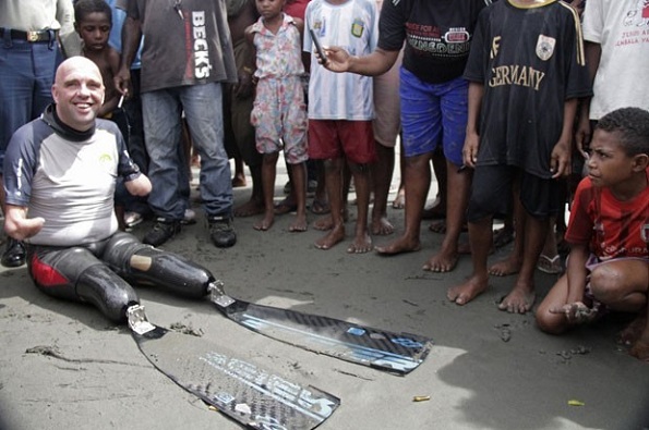 Philippe Croizon sorri ao ser recebido com curiosidade pelos moradores da vila de Pasar Skow, na ilha indonésia de Papua (Foto: Levi Cunding/AFP)