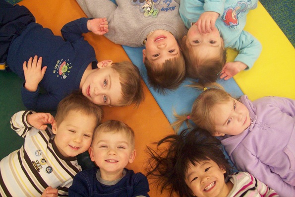Crianças deitadas sobre um tapete e sorrindo