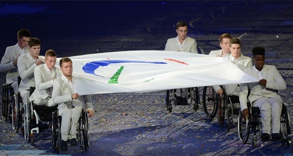 Cadeirantes carregam bandeira do Comitê Paraolímpico durante cerimônia de abertura dos Jogos 