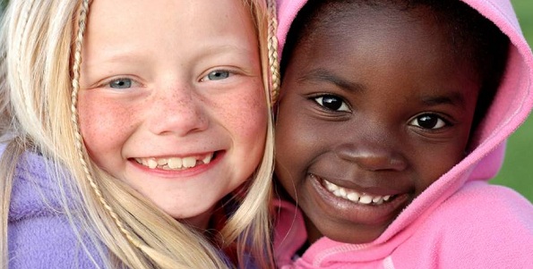duas crianças sorrindo, uma negra e outra branca