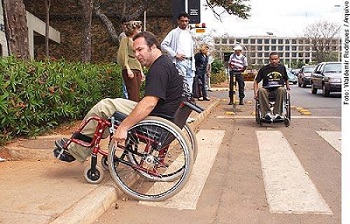 Homem cadeirante tentando subir na calçada