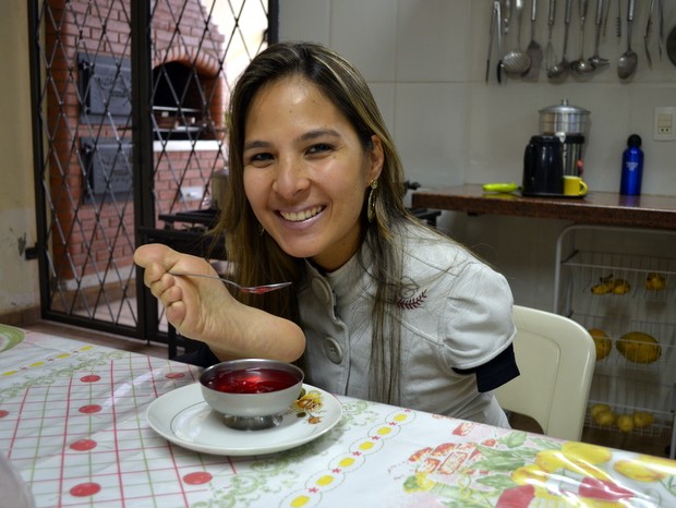 Sem o auxílio de ninguém, Carolina utiliza os pés para se alimentar (Foto: Fernanda Zanetti/G1)