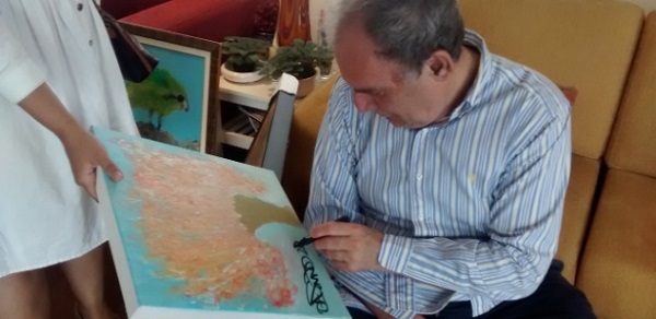 Osmar Santos assina um de seus quadros, que deu de presente à esposa de seu filho